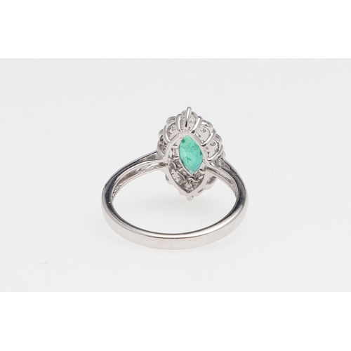 1140 - AN EMERALD AND DIAMOND CLUSTER RING. the marquise-shaped emerald is set within a surround of round b... 