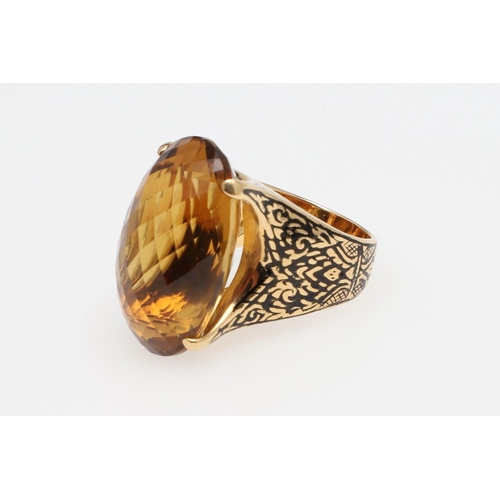 1142 - A LARGE CITRINE DRESS RING. the large oval faceted citrine set in 18ct gold with black enamelled sho... 