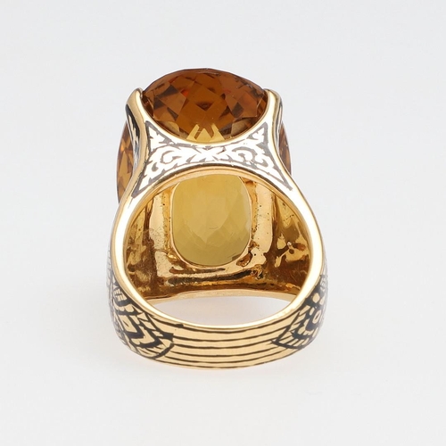 1142 - A LARGE CITRINE DRESS RING. the large oval faceted citrine set in 18ct gold with black enamelled sho... 