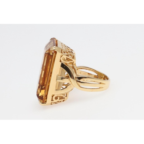 1143 - A LARGE CITRINE DRESS RING. The 18ct gold ring set with a  large rectangular citrine in pierced gall... 