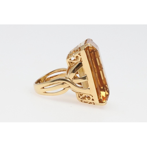 1143 - A LARGE CITRINE DRESS RING. The 18ct gold ring set with a  large rectangular citrine in pierced gall... 