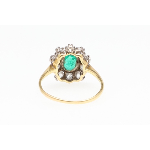 1144 - AN EMERALD AND DIAMOND CLUSTER RING. the oval-shaped emerald is set within a surround of circular ol... 