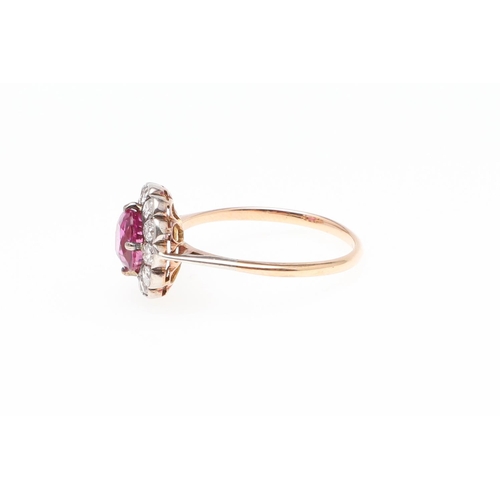 1145 - A PINK SAPPHIRE AND DIAMOND CLUSTER RING. the cushion-shaped pink sapphire is set within a surround ... 