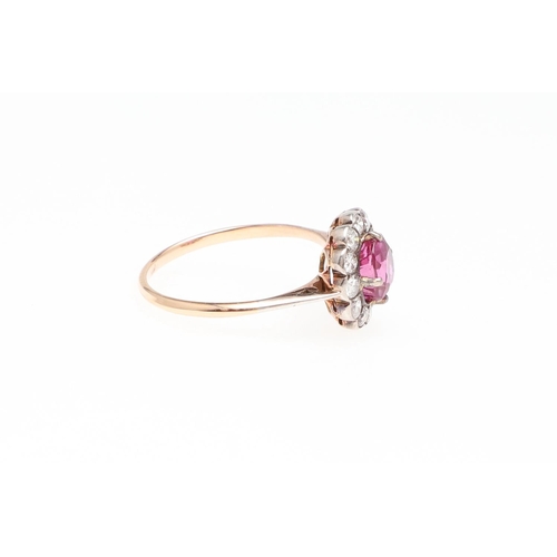 1145 - A PINK SAPPHIRE AND DIAMOND CLUSTER RING. the cushion-shaped pink sapphire is set within a surround ... 