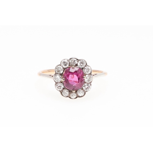 1145 - A PINK SAPPHIRE AND DIAMOND CLUSTER RING. the cushion-shaped pink sapphire is set within a surround ... 