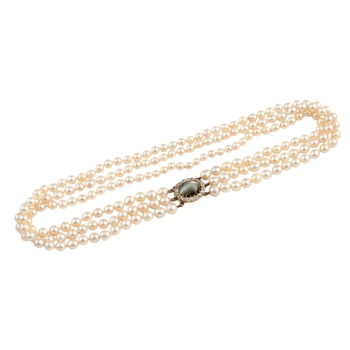 1149 - A THREE ROW CULTURED PEARL CHOKER. the pearls measure approximately 5.5-6.5mm and are set to a yello... 