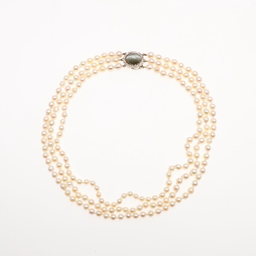 1149 - A THREE ROW CULTURED PEARL CHOKER. the pearls measure approximately 5.5-6.5mm and are set to a yello... 