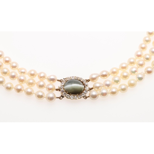 1149 - A THREE ROW CULTURED PEARL CHOKER. the pearls measure approximately 5.5-6.5mm and are set to a yello... 