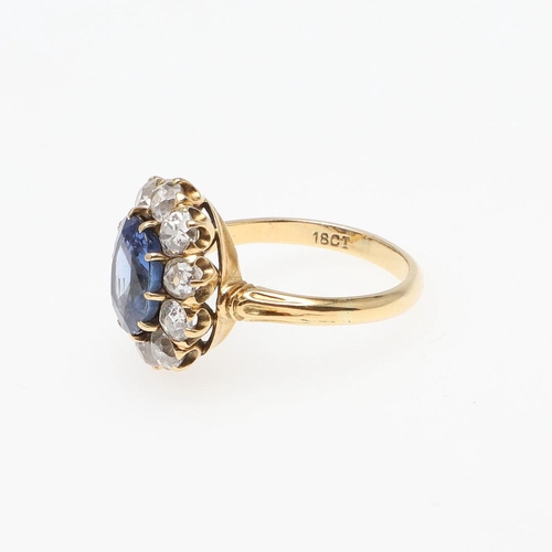 1153 - A SAPPHIRE AND DIAMOND CLUSTER RING. the oval-shaped sapphire weighs approximately 4.40 carats and i... 