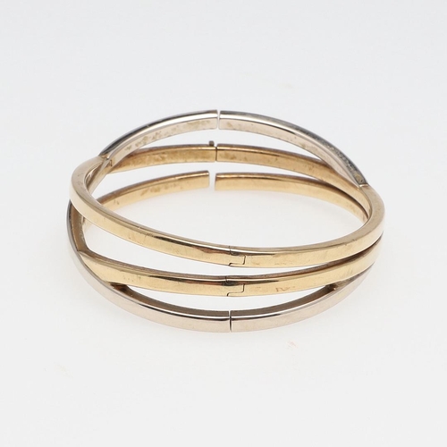 856 - A 9CT TWO COLOUR GOLD TRIPLE BAND BANGLE. formed as three oval-shaped interlocking gold bands, inter... 