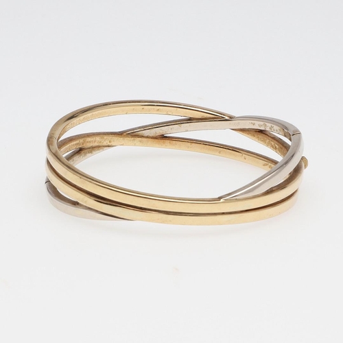 856 - A 9CT TWO COLOUR GOLD TRIPLE BAND BANGLE. formed as three oval-shaped interlocking gold bands, inter... 