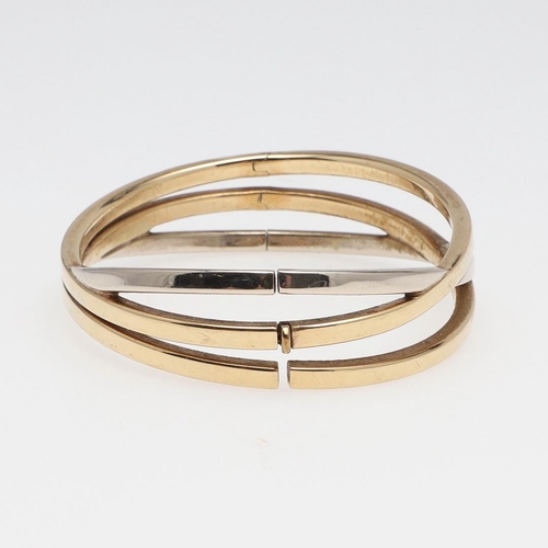 856 - A 9CT TWO COLOUR GOLD TRIPLE BAND BANGLE. formed as three oval-shaped interlocking gold bands, inter... 