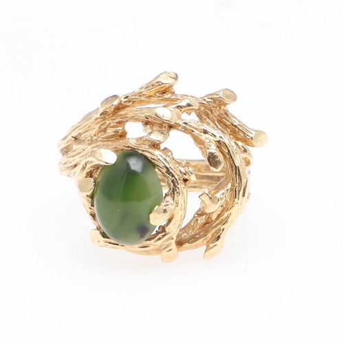 985 - A JADE AND GOLD DRESS RING. the 14ct gold openwork textured mount is set with an oval-shaped section... 