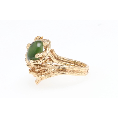 985 - A JADE AND GOLD DRESS RING. the 14ct gold openwork textured mount is set with an oval-shaped section... 