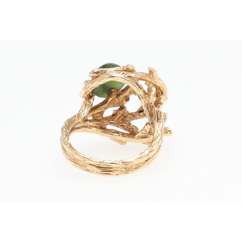 985 - A JADE AND GOLD DRESS RING. the 14ct gold openwork textured mount is set with an oval-shaped section... 