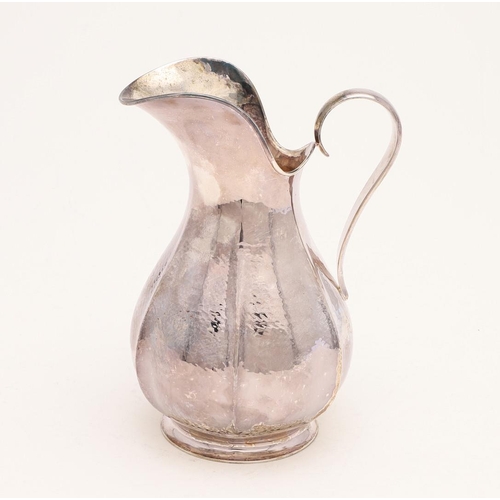 144 - A MODERN CHANNEL ISLES JUG. with a lobed and bellied body, a scroll handle and with a hammered finis... 