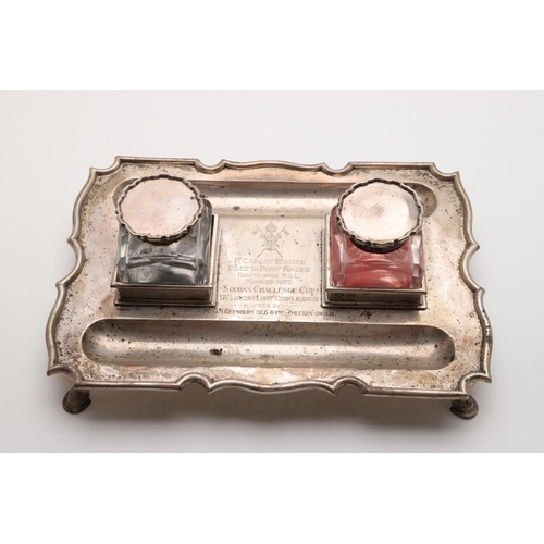 169 - AN EDWARDIAN INKSTAND. shaped rectangular outline, raised on four hoof feet, inscribed in the centre... 