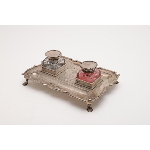 169 - AN EDWARDIAN INKSTAND. shaped rectangular outline, raised on four hoof feet, inscribed in the centre... 