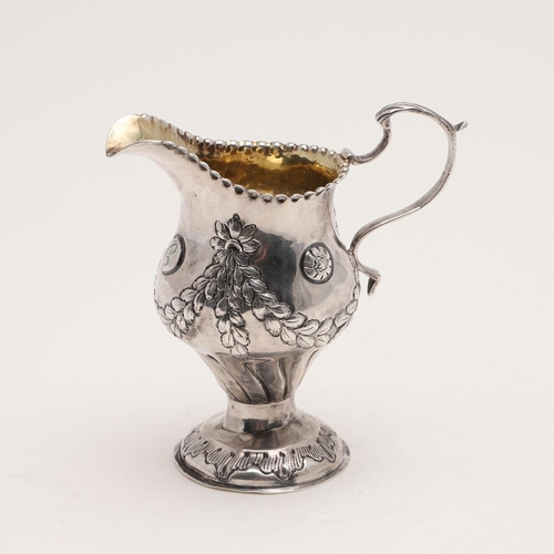 190 - A GEORGE III BALUSTER CREAM JUG. with a punched border, a leaf-capped 'S'-scroll handle, the body de... 