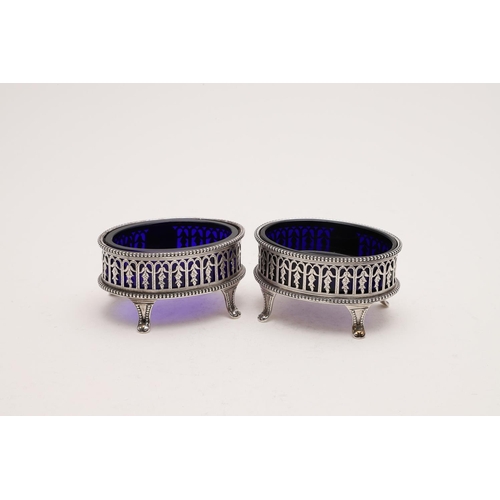 191 - A PAIR OF VICTORIAN OVAL SALTS. with bead borders, pierced sides and on four legs (blue glass liners... 