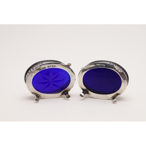 191 - A PAIR OF VICTORIAN OVAL SALTS. with bead borders, pierced sides and on four legs (blue glass liners... 