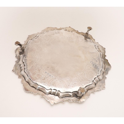 195 - A GEORGE II SALVER. of shaped circular outline, with a husk & scroll border, chased decoration in th... 