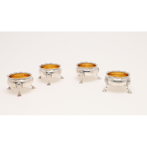 196 - A SET OF FOUR GEORGE II CIRCULAR SALTS. with textured borders, gilt interiors and raised on hoof fee... 