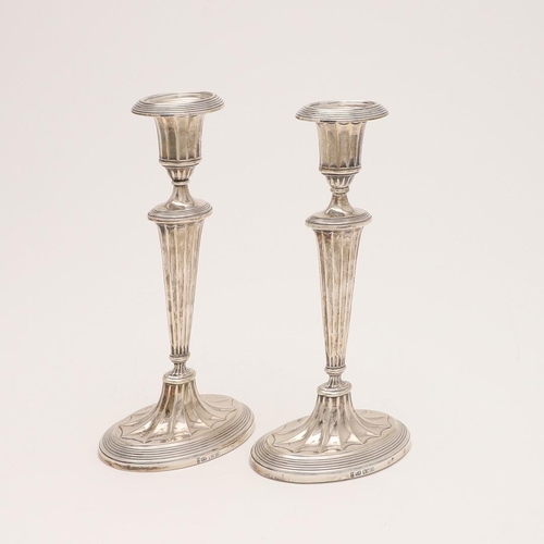 222 - A PAIR OF EDWARDIAN CANDLESTICKS. on oval bases (loaded), with bats-wing fluting and reeded borders,... 