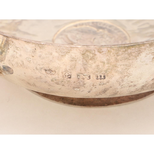 263 - A GEORGE V SMALL CIRCULAR BOWL. with an applied border, inset with a coin and engraved with the embl... 