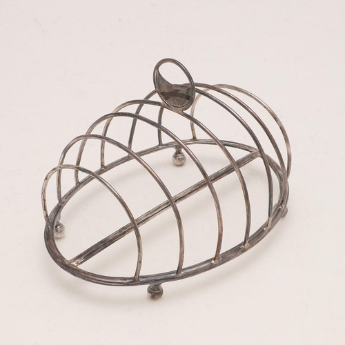 267 - A GEORGE III OVAL TOAST RACK. with seven arched bars, a central crescent handle and raised on four l... 