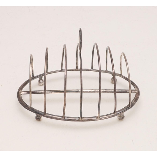 267 - A GEORGE III OVAL TOAST RACK. with seven arched bars, a central crescent handle and raised on four l... 