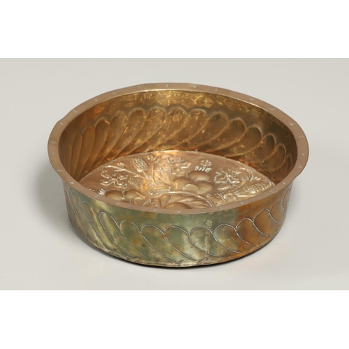 1469 - AN ANTIQUE BRASS REPOUSSE ALMS BOWL. the central panel depicting leopard head, berry and leaf decora... 