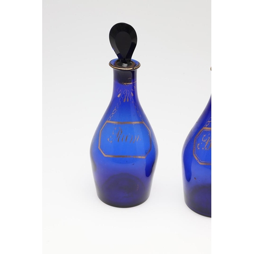 1504 - A SET OF THREE REGENCY BLUE GLASS DECANTERS. each with faux gilt labels for Rum, Brandy and Hollands... 