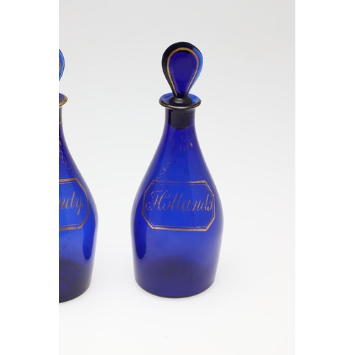 1504 - A SET OF THREE REGENCY BLUE GLASS DECANTERS. each with faux gilt labels for Rum, Brandy and Hollands... 