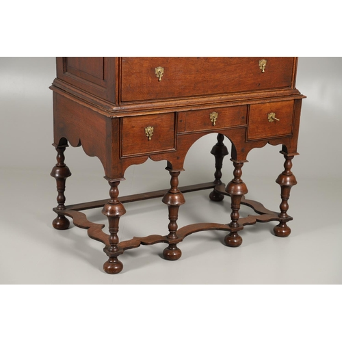 1605 - AN EARLY 18TH CENTURY OAK CHEST ON STAND. the moulded cornice over panelled sides, two short and thr... 