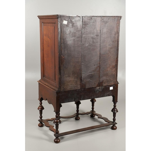 1605 - AN EARLY 18TH CENTURY OAK CHEST ON STAND. the moulded cornice over panelled sides, two short and thr... 