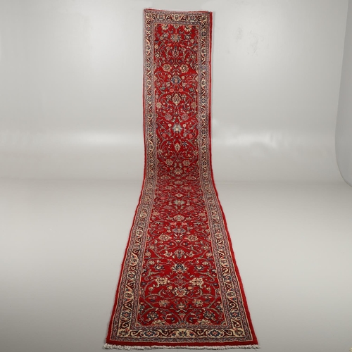 1732 - A NARROW SAROUKH RUNNER, WEST PERSIA, CIRCA 1970. the raspberry field of scrolling vines and palmett... 