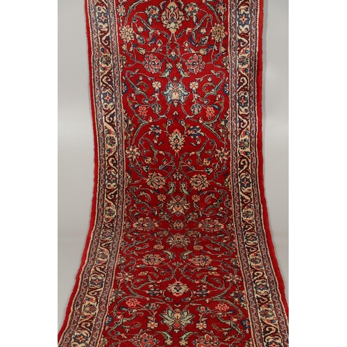 1732 - A NARROW SAROUKH RUNNER, WEST PERSIA, CIRCA 1970. the raspberry field of scrolling vines and palmett... 