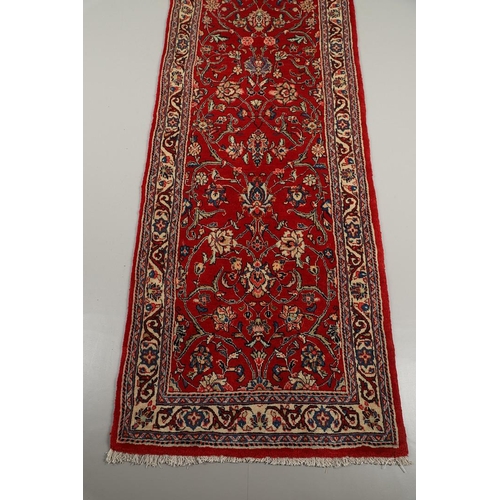 1732 - A NARROW SAROUKH RUNNER, WEST PERSIA, CIRCA 1970. the raspberry field of scrolling vines and palmett... 