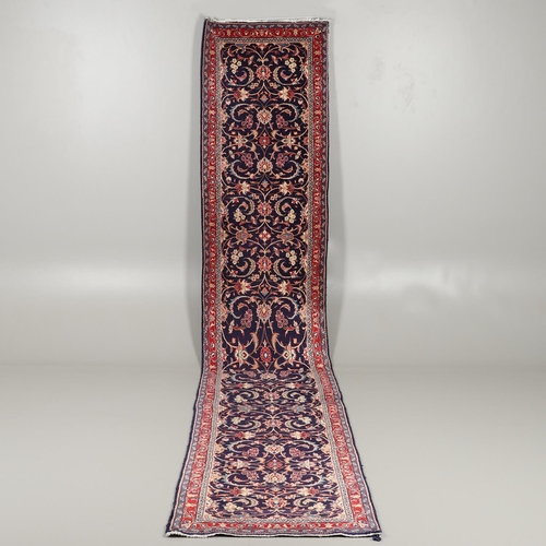 1743 - A NARROW PERSIAN RUNNER, PROBABLY SAROUKH, CIRCA 1970. the indigo field of scrolling vines and palme... 