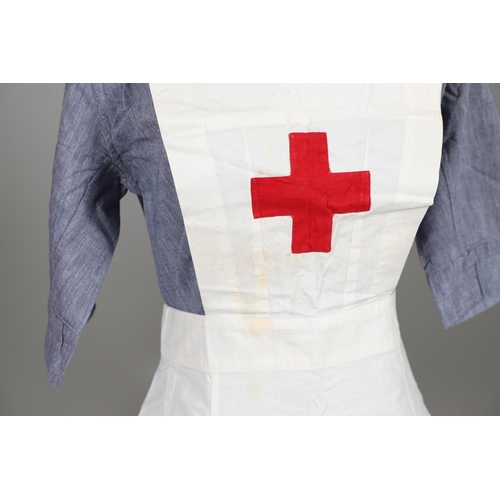 677 - VINTAGE NURSES UNIFORMS & RED CROSS APRONS. A qty of Nurses Uniforms to include a blue Chambray cott... 