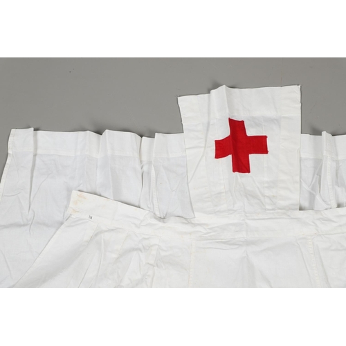 677 - VINTAGE NURSES UNIFORMS & RED CROSS APRONS. A qty of Nurses Uniforms to include a blue Chambray cott... 