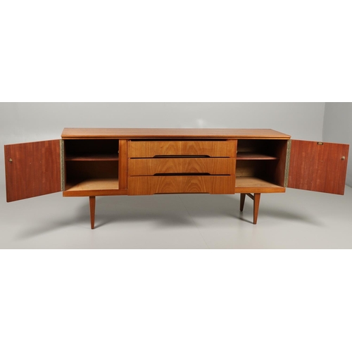 773 - MID CENTURY TEAK SIDEBOARD - BEAUTILITY. A large teak sideboard with a curved front, with three cent... 