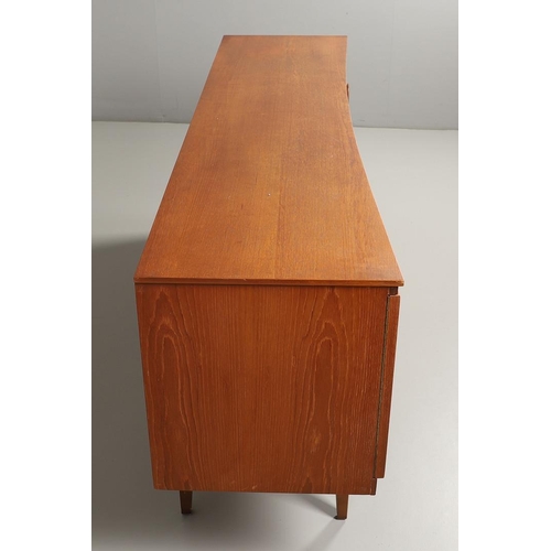 773 - MID CENTURY TEAK SIDEBOARD - BEAUTILITY. A large teak sideboard with a curved front, with three cent... 