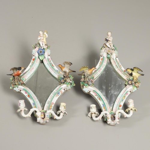 865 - PAIR OF CONTINENTAL PORCELAIN MIRRORS. Probably German, the shaped mirrors each mounted with cherub ... 