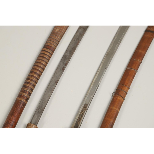 110 - TWO SIMILAR BURMESE DHA TYPE SWORDS AND SCABBARDS. A Burmese sword with a 59cm shaped blade with sha... 