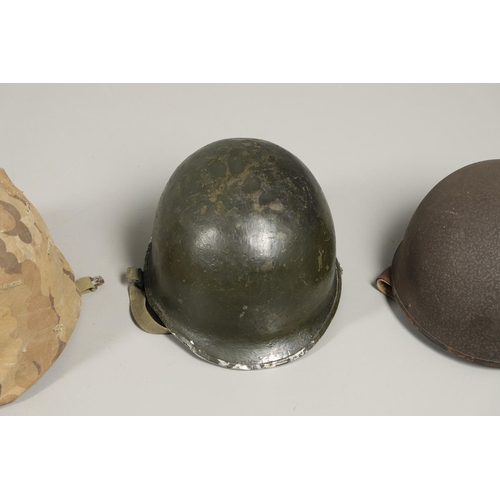 435 - THREE SECOND WORLD WAR OR LATER AMERICAN HELMETS. An American Steel helmet with green painted shell,... 