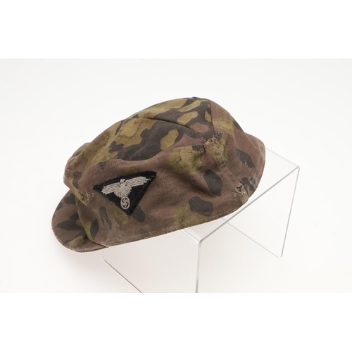 447 - A SECOND WORLD WAR GERMAN WAFFEN-SS CAMOUFLAGE SKI CAP. A camouflage pattern ski cap with a zinc sku... 