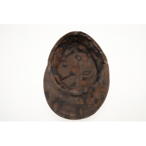 447 - A SECOND WORLD WAR GERMAN WAFFEN-SS CAMOUFLAGE SKI CAP. A camouflage pattern ski cap with a zinc sku... 