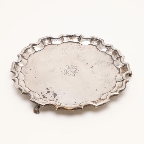 112 - A GEORGE V SMALL SILVER SALVER. of shaped circular outline, with a moulded border, raised on three s... 